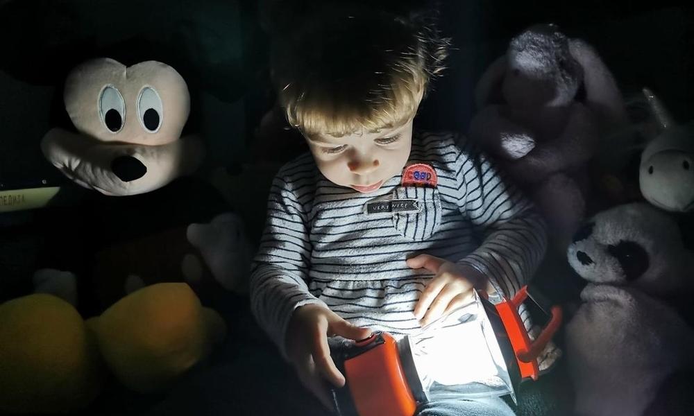 A child sat with teddies and a battery light