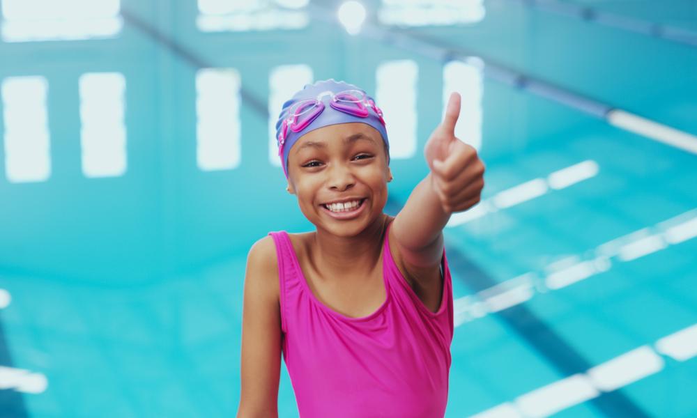 Girl in swimming pool with thumbs up 