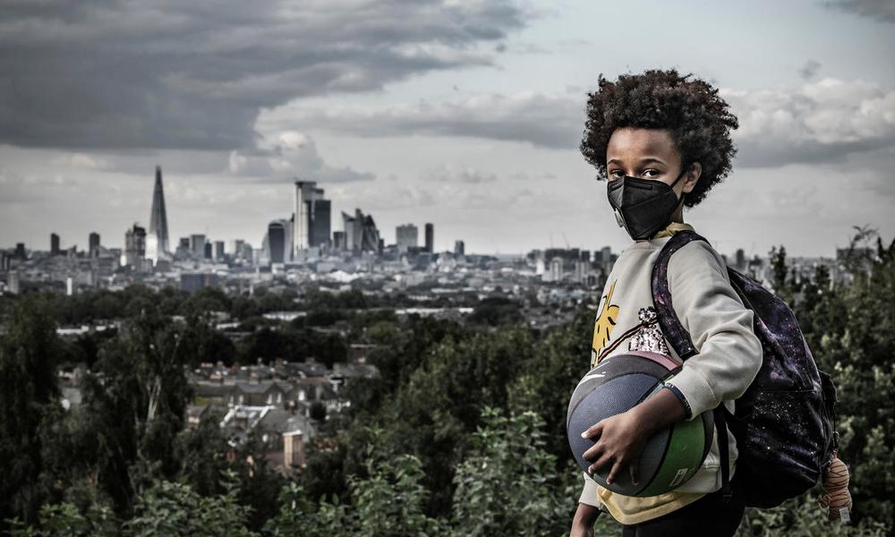 Afrika, 8, holds a ball and wears a mask to protect against air pollution. Dawson Heights, south east London.