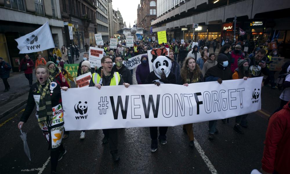 Thousands march through Glasgow during COP26, with WWF supporters holding a banner saying We Won't Forget