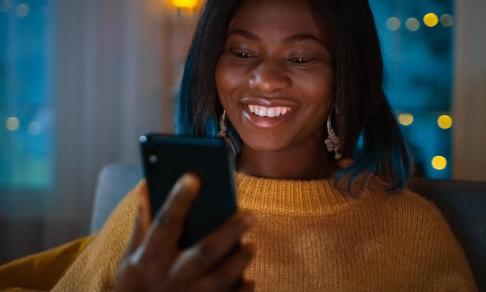 Woman smiles while looking at her mobile phone. 
