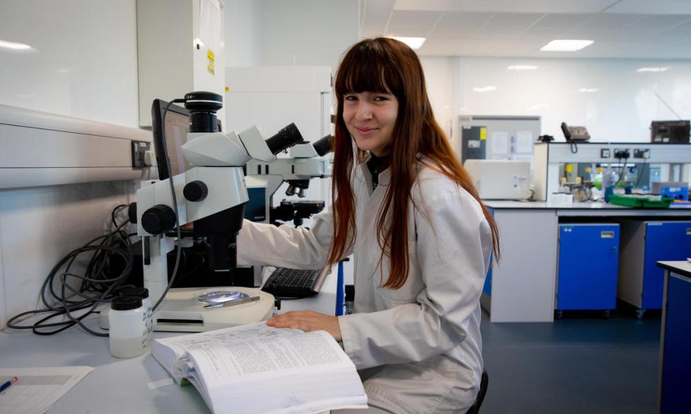 Portrait of Issy Inman using a microscope to study marine life connected with seagrass. Swansea University, Swansea, Wales, UK.