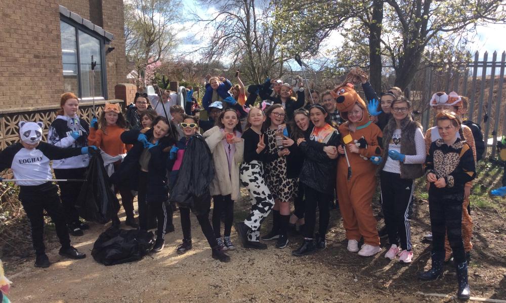 A group of school children, some in animal fancy dress, outside their school