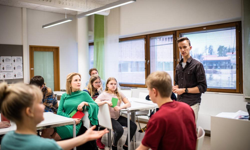 Male teacher standing up in front of class of secondary aged students