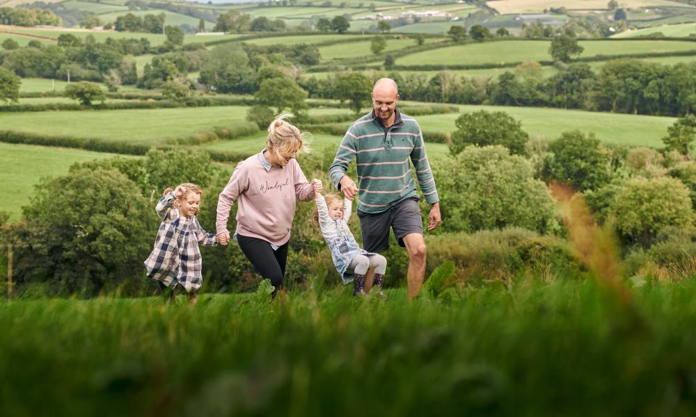 The family at Rest Farm, both parents and two children, walk through the field.