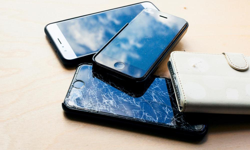 Four unused or broken mobile phones in pile 