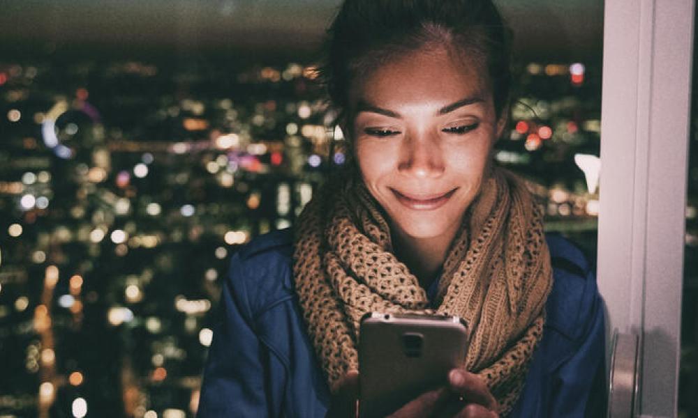 Person looking at phone with city backdrop