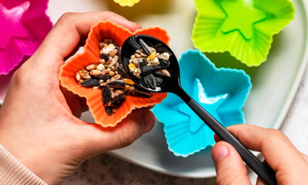 Bird seed being spooned into muffin tin Bird seed being spooned into muffin tin