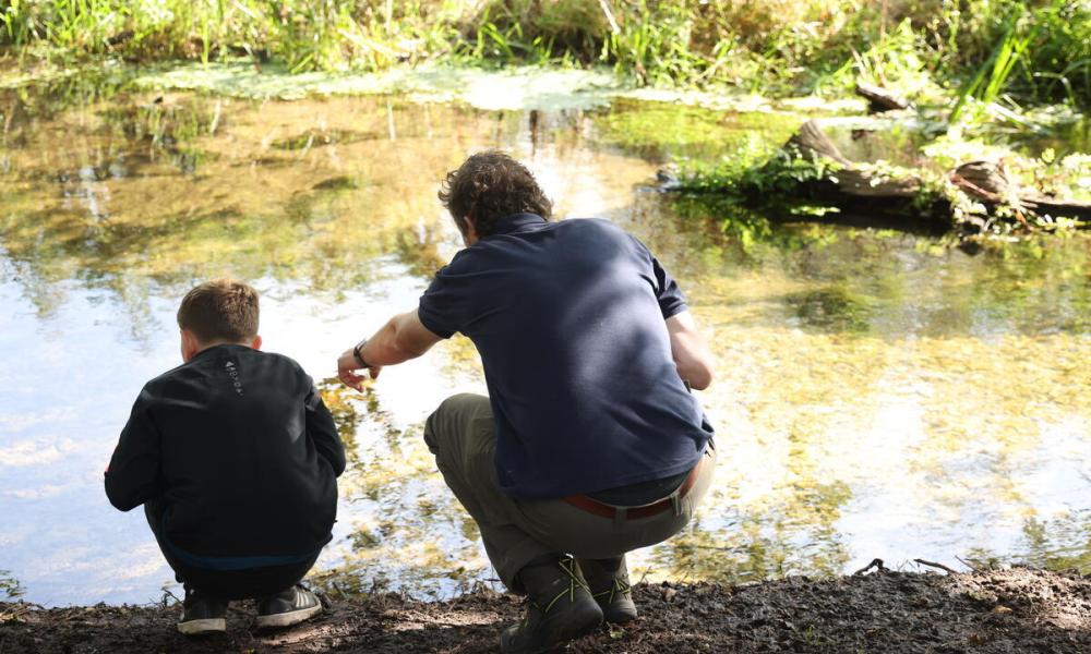 Man and boy crouched next to a river