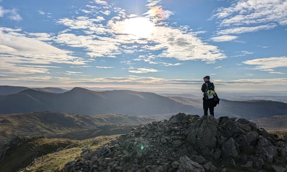 A hiker at the top of a mountain overlooking the view