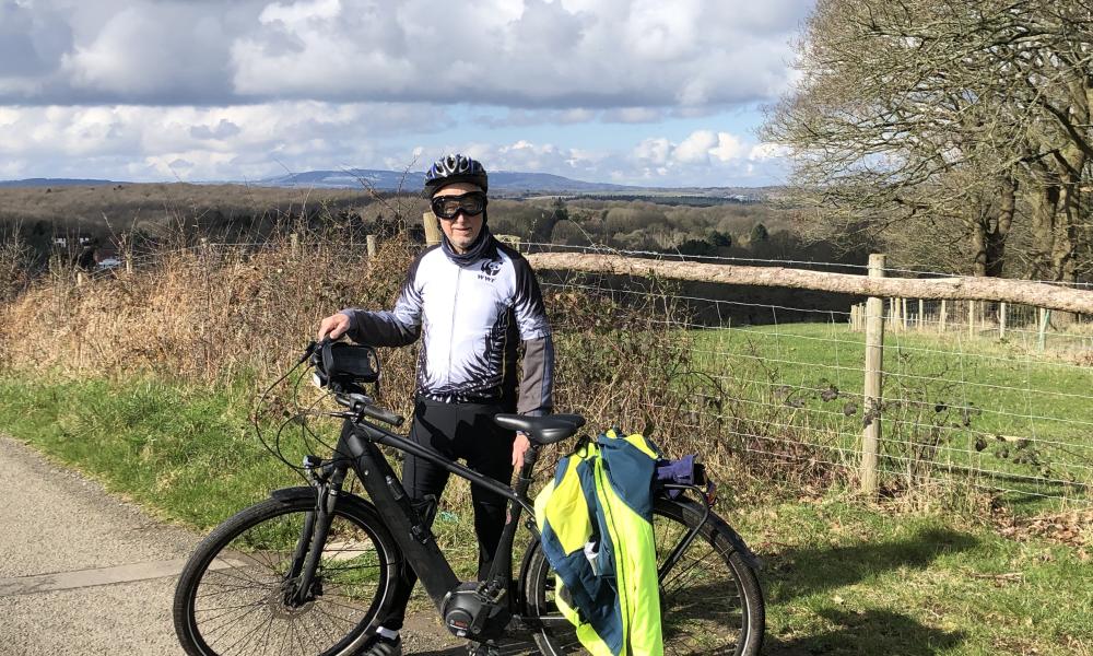 Man in cycling excercise gear stood with his boke in English countryside