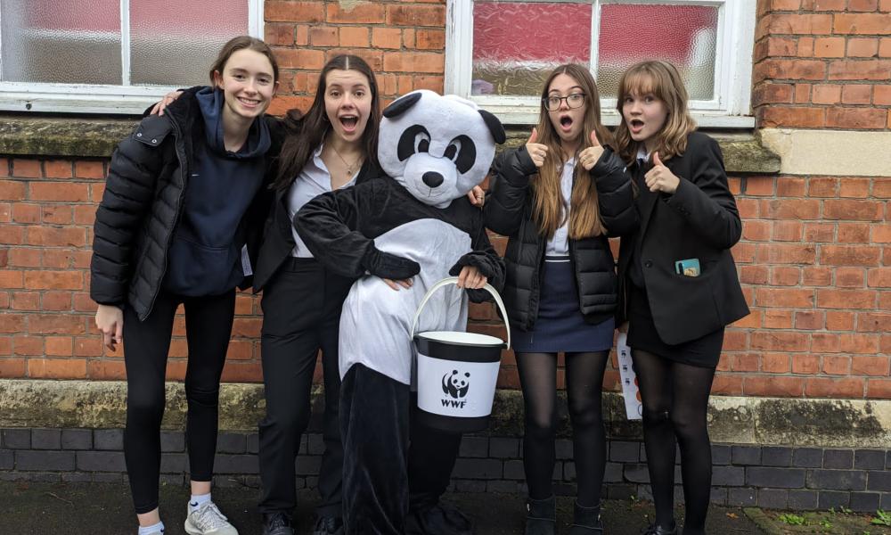 A large group young people, the WWF mascot Chi Chi and a WWF bucket. Fundraising for WWF.