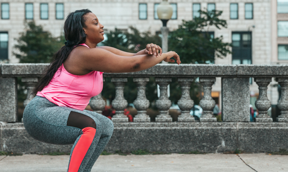 Woman completing squats in city setting