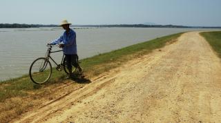 Farmer pushing his bike on a dyke built to prevent the Dongting Lake's waters to flood the polders. Dongting Lake, Hunan Province, China