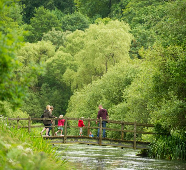 A family cross a bridge, River Itchen, Hampshire, UK