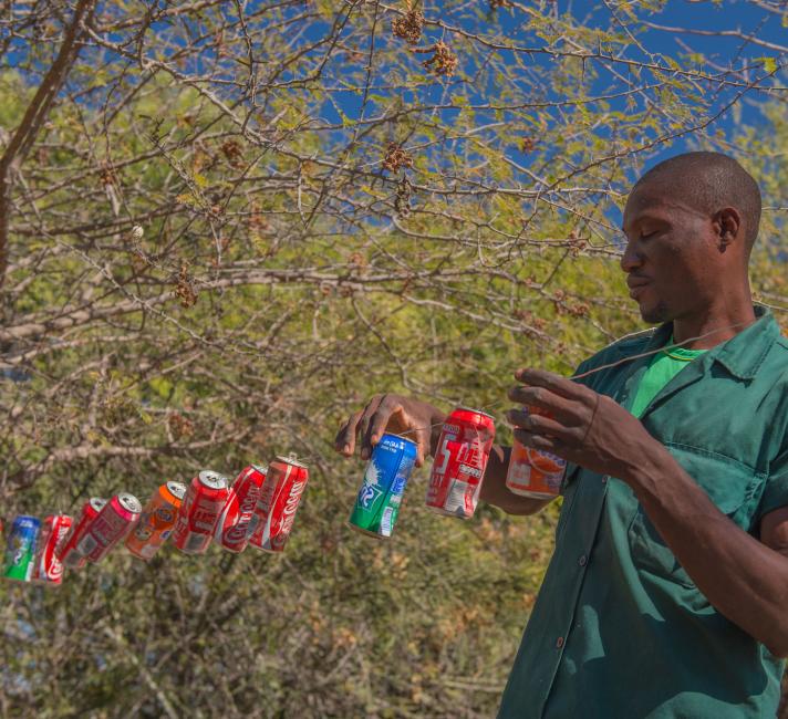 Humphrey Mwanga, a community game guard putting up a tin-can fence
