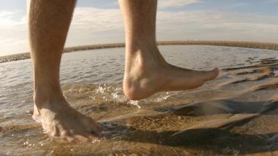 Man's bare feet walking in the water