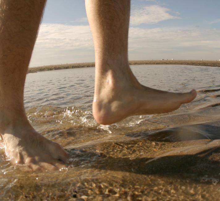 Man's bare feet walking in the water