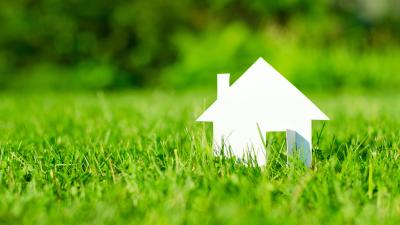House in green field representing financial investment in renewable energy and sustainable development.