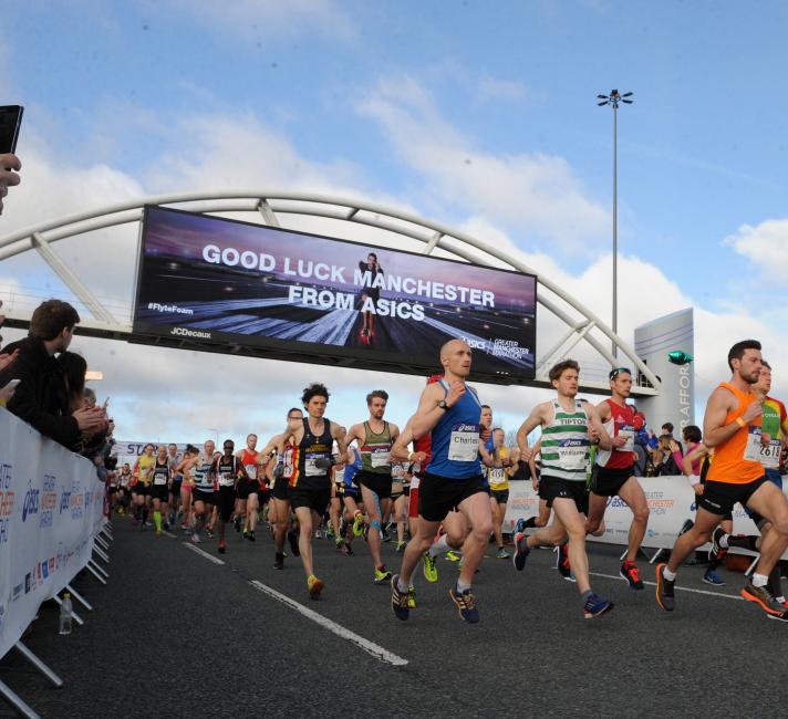 Runners in the Manchester Marathon under good luck sign