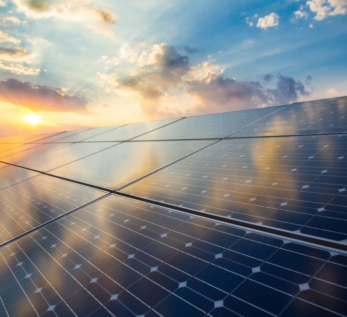 Renewable energy stock image of photovoltaic modules on the background of sunset and cloudy sky. 