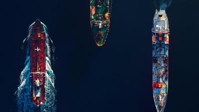 Aerial top view of a busy harbour. Large commercial ships cruising in the port.