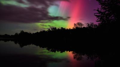 A vibrant aurora borealis display with soft pink, purple, and green lights glowing through a partially cloudy sky A vibrant aurora borealis display with soft pink, purple, and green lights glowing through a partially cloudy sky