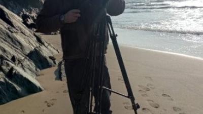 A member of the SAMS team with a camera set up on a tripod on the beach in Pembrokeshire.
