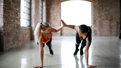 two women doing a high 5 whilst attempting push ups