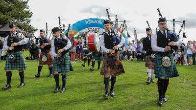 Photo of four men wearing kilts and playing bagpipes
