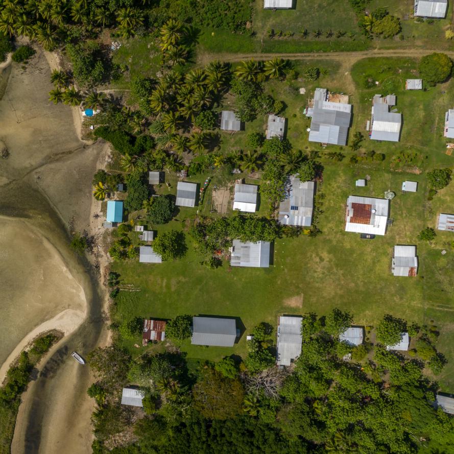 Aerial shot of the tide coming in at Raviravi village. During king tide (highest tide of the month during full moon) the seawater regularly floods the houses closest to the beach. Vanua Levu, Fiji. 