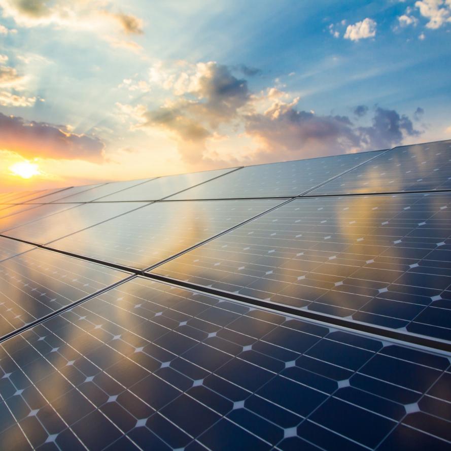 Renewable energy stock image of photovoltaic modules on the background of sunset and cloudy sky. 