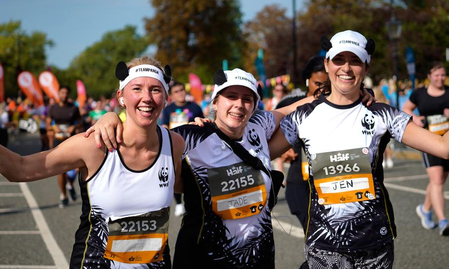 Three WWF runners smiling and waving as they take part in the Royal Parks Half Marathon