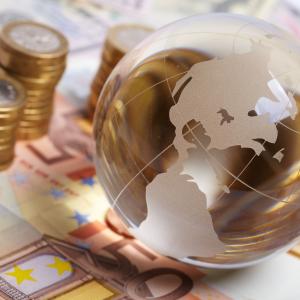 Currency and planet on a table representing global economy - © Shutterstock