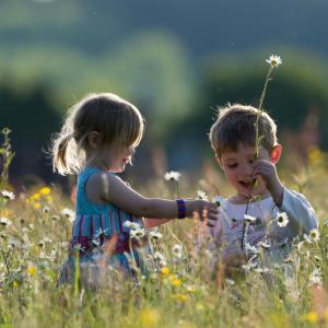 Young children, a boy and girl, playing in hay meadow