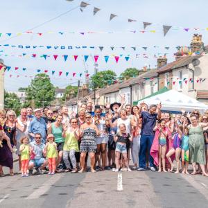 Street party on a sunny day, group photo of people on the closed road with bunting hanging over the street