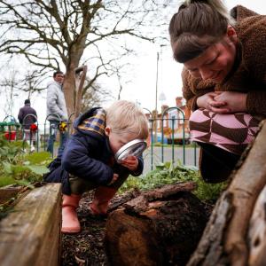 Little boy looking through magnified glass in Belgrave Community inner-city garden in Leicester