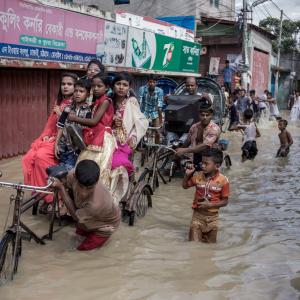 Young people celebrating Eid, a religious festival, travelling by rickshaw during a heavy tidal surge.