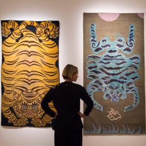 A woman looking at two rug artworks on the wall