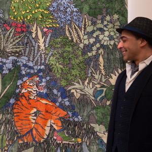 Man smiling while looking at an artwork rug hung on a wall