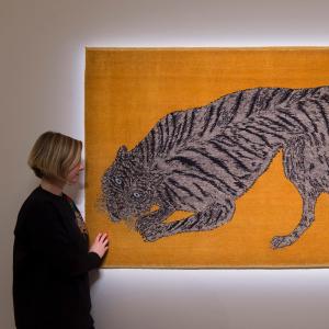 An image of a woman stood next to an artwork depicting a tiger