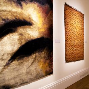 Orange and black rug artworks hung on a wall