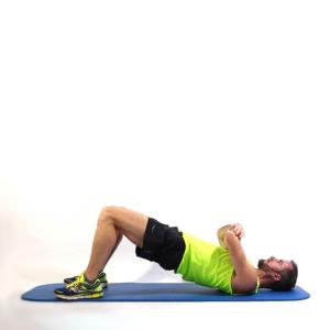 side view image of a man lying on a yoga mat in bridge pose